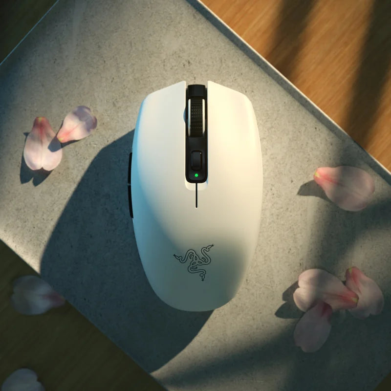 White Razer gaming mouse on a textured surface with flower petals