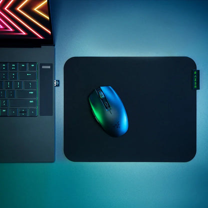 Gaming mouse on a mouse pad next to a laptop with RGB lighting