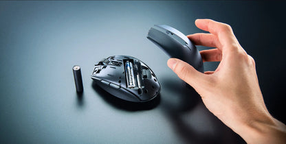 Hand holding a wireless computer mouse with a battery on a dark background